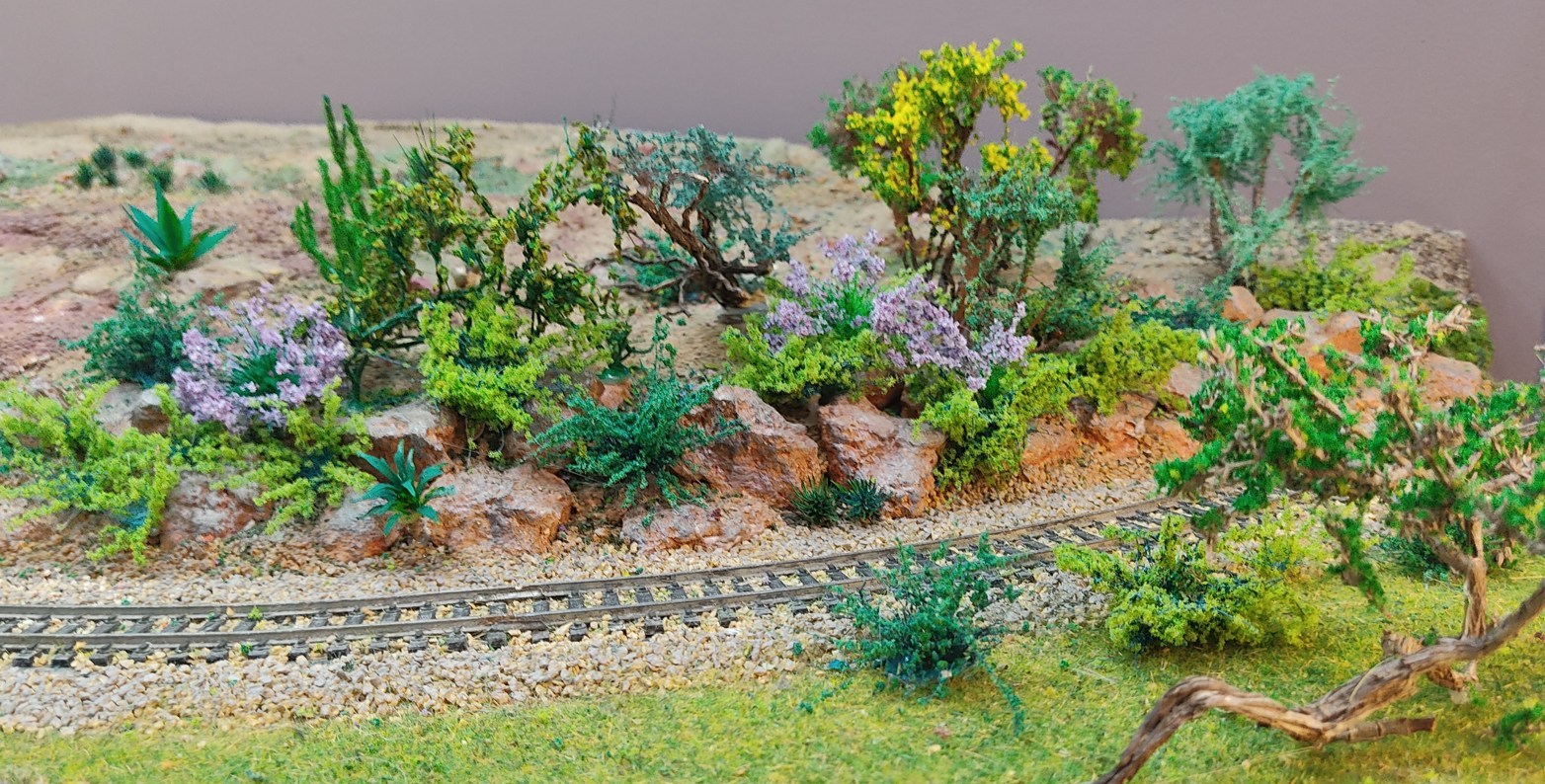 Diorama de Nature Center con arbustos en flor, vegetación y vía de tren integrados en el paisaje